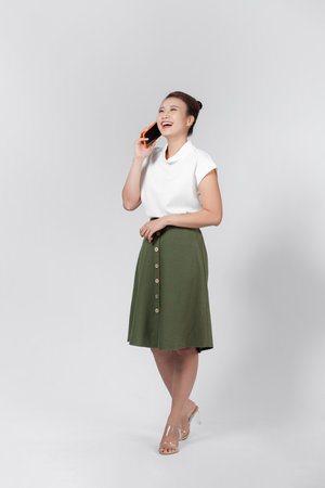 Full length portrait of the charming lady speaking phone toothy smile isolated on white backgroundの写真素材