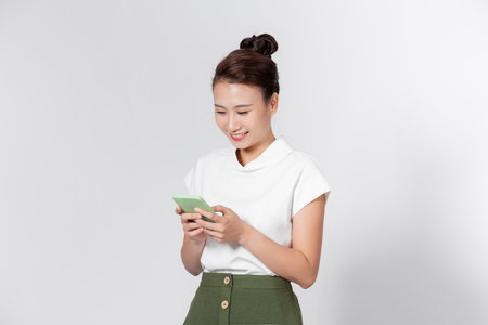 Beautiful smiling asian woman checking mail on mobile phoneの写真素材