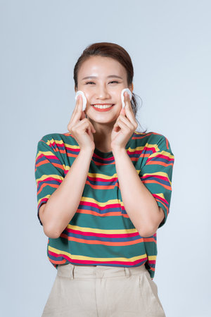 woman with a sponge blue background cotton pad problem skinの写真素材