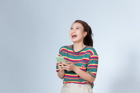 pretty woman laughing out loud at some hilarious joke and using a smartphoneの写真素材