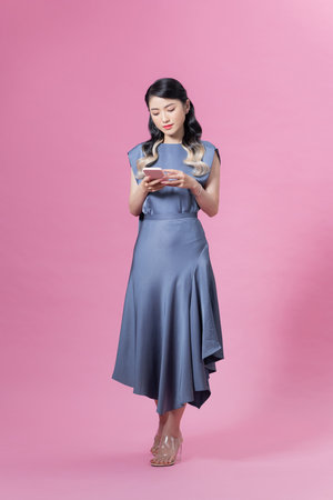 pretty woman using cell phone chatting with boyfriend date web service isolated over pink backgroundの写真素材