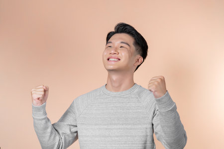 Young handsome man very happy and excited doing winner gesture with arms raised, smiling and screaming for success.の写真素材