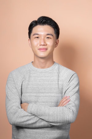 Portrait of attractive cheerful experienced intelligent man folded arms isolated over beige backgroundの写真素材