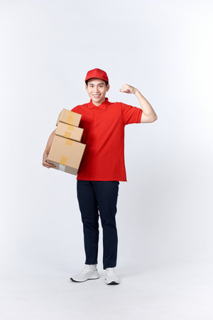 Professional delivery guy employee man in red cap T-shirt uniform workwear work as dealer courier hold cardboard box show musclesの写真素材