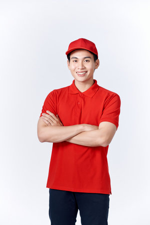 Professional smiling confident male employee in cap, t-shirt courier dealer holding hands crossed foldedの写真素材