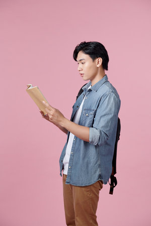 Youngman opening book for reading, relax or study searching information in books for knowledge, pink backgroundの写真素材