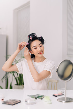 Portrait of happy beautiful woman in hairrollers - isolated on livingroom backgroundの写真素材