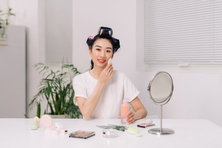 Young attractive lady using face toner and cotton pad, home interiorの写真素材