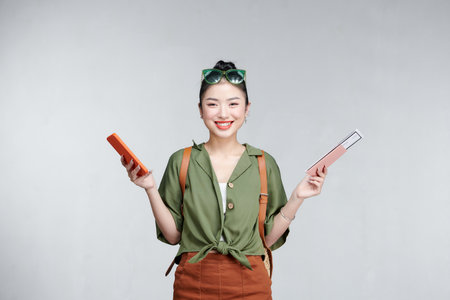 Asian woman traveler holding mobile phone and  summer travelling concept over gray backgroundの写真素材