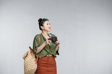 Happy Asian woman traveler standing and holding cameraの写真素材