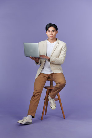 Young Asian business man using laptop computer and sitting on chairの写真素材