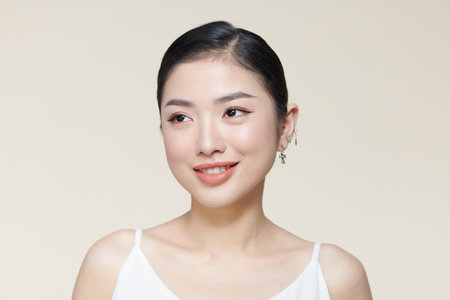 Happy young woman face with clear skin on brown background, closeup portraitの写真素材