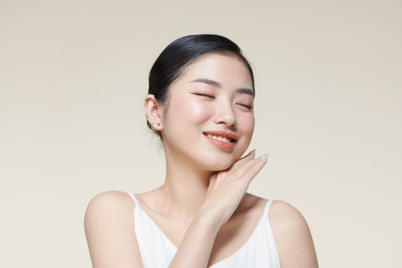 Beautiful young woman with clean fresh skin touching her faceの写真素材
