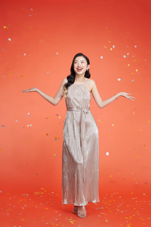 Image of happy young woman standing isolated over red background over confettiの写真素材