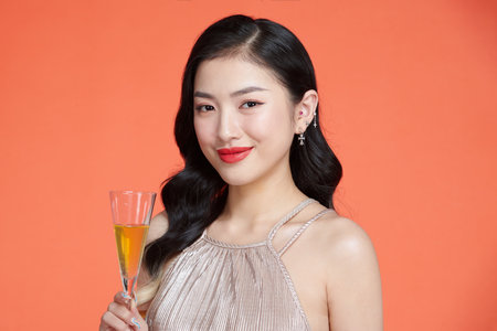 Attractive asian woman laughs and holds glass of champagneの写真素材