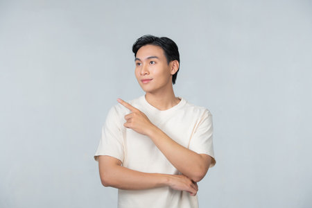 Asian man smiling when looking and pointing to the right sideの写真素材