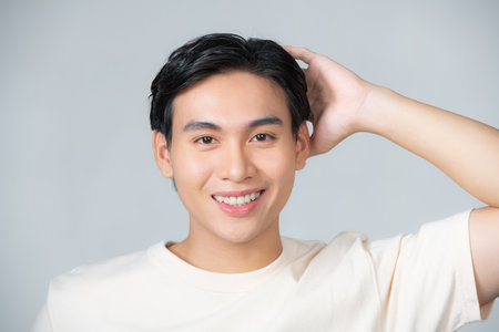 Asian man touches his hair looking at the camera.の写真素材