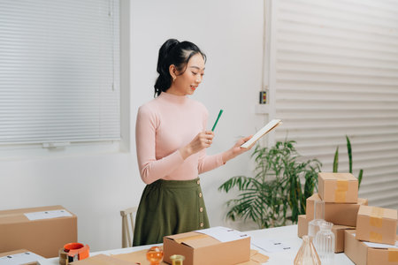 Young pretty asian entrepreneur warehouse worker working and checking product inventory in warehouse showroom.の写真素材