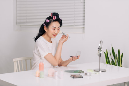 Daily makeup routine, Asian young women looks in the mirror during putting makeup on her face.の写真素材