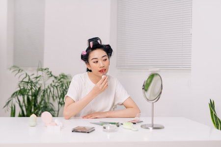Young woman doing her makeup in the mirror.の写真素材