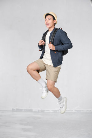 Happy young traveling man jumping isolated on white.の写真素材