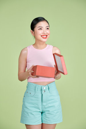 Emotional brunette young woman opens gift box, having overjoyed ecstatic facial expressionの写真素材
