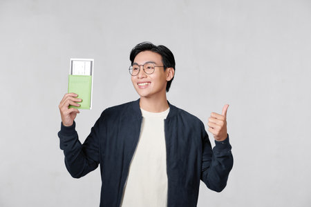 Young asian man hold passport ticket doing winner's gestureの写真素材