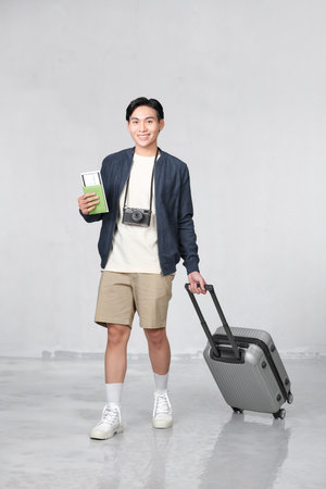 Portrait of surprised excited asian man holding passport and boarding pass ticketの写真素材