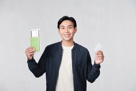 Joyful man holding passport with tickets and showing plastic credit cardの写真素材