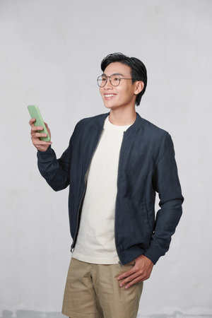 Portrait of cheerful man using cellphone and smiling, reading good news message, enjoying mobile applicationの写真素材
