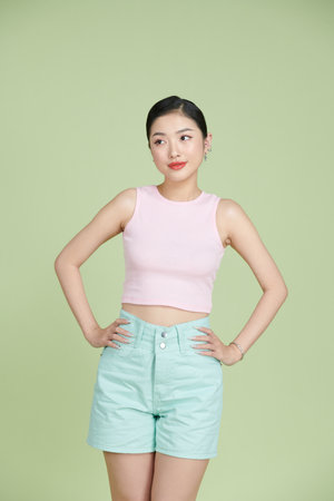happy smiling young woman with hands on hips posing over green backgroundの写真素材