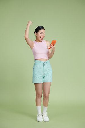 Full length of youth excited girl celebrate luck use smartphone fists handの写真素材