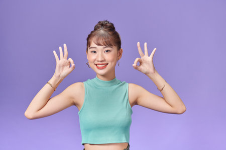 Portrait happy Asian woman shows ok sign looking at cameraの写真素材
