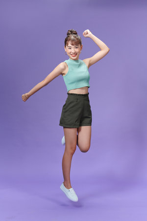 Full length portrait of an excited young woman jumping and celebratingの写真素材