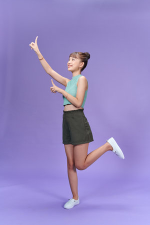 Cheerful excited asian woman use finger pointing to side with productの写真素材