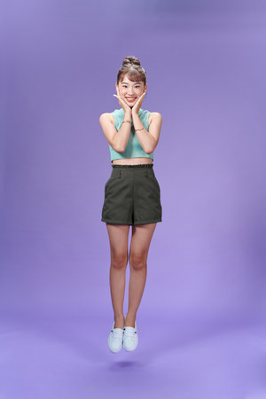 Full size photo of happy positive young woman jump up hold hands face smileの写真素材