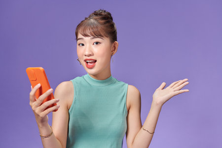 Young Asian woman holding phone and looking up with excitementの写真素材