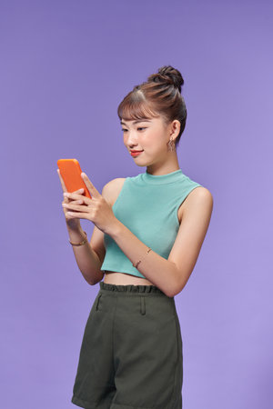 Smiling young woman girl using smartphone with wireless connection isolated on purpleの写真素材