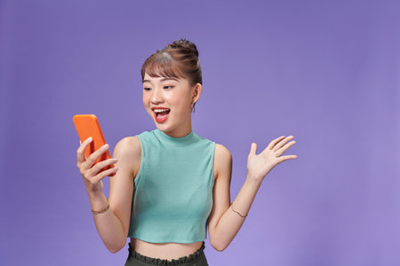 Young Asian woman holding phone in hand with surprised lookの写真素材