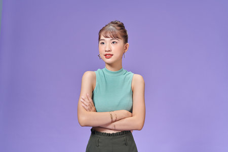 Young woman isolated on purple background who feels confident, crossing arms with determination.の写真素材