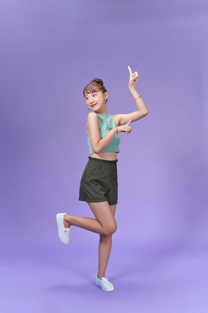 woman smiling happily and pointing to side and upwards with both hands showing object in copy spaceの写真素材