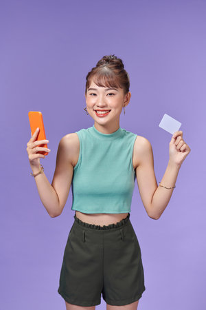 Happy young woman using mobile phone and credit card.の写真素材