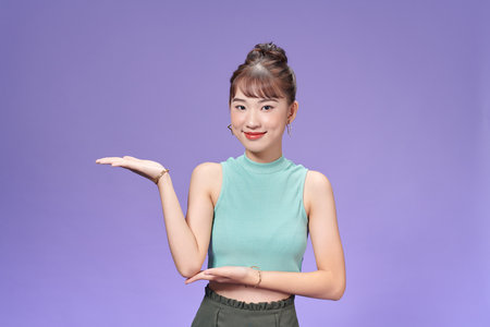 Portrait of attractive cheerful girl holding on palm copy space choosingの写真素材