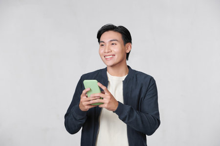 Smart casual asian man using smartphone in studio backgroundの写真素材