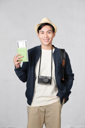 Portrait of happy young guy holding passport and boarding pass against white backgroundの写真素材