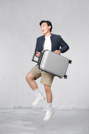 Excited fun Caucasian tourist man with baggage, ready to travel, jumpingの写真素材