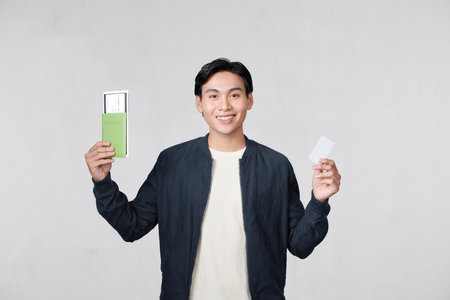 Studio portrait of handsome young man holding passport and banking cardの写真素材