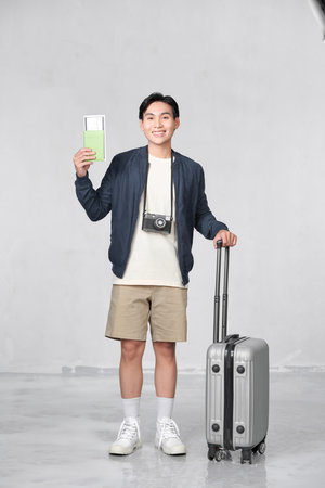 A satisfied young man looking camera holding passport and tickets isolated over white backgroundの写真素材