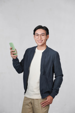 Smart casual asian man using smartphone in studio backgroundの写真素材
