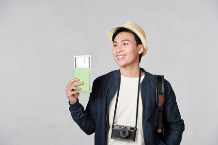 Portrait of surprised excited asian man holding passport and boarding pass ticketの写真素材